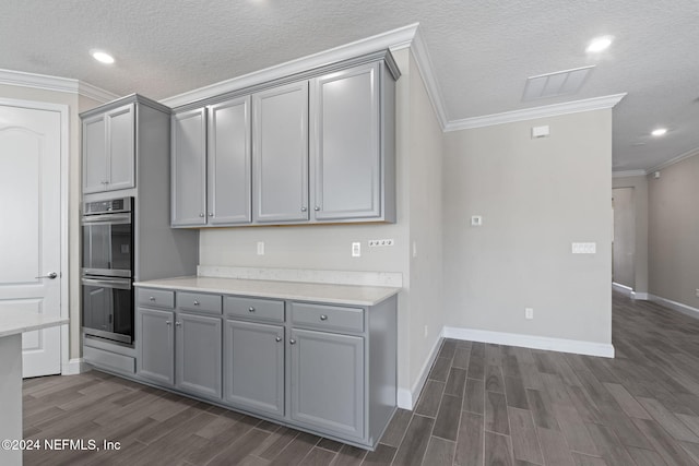 kitchen with gray cabinetry, stainless steel double oven, dark hardwood / wood-style flooring, a textured ceiling, and ornamental molding