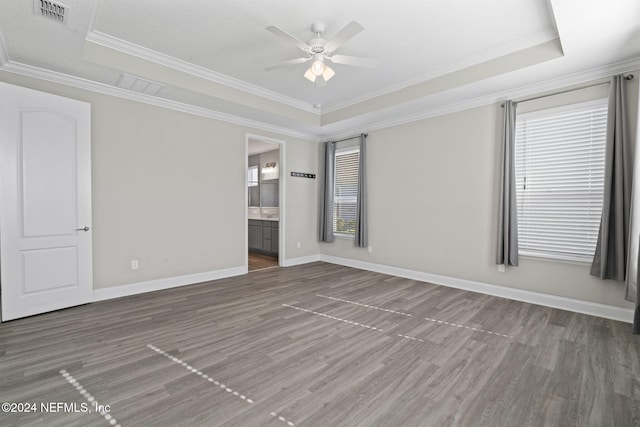 spare room featuring a raised ceiling, ceiling fan, dark hardwood / wood-style floors, and ornamental molding