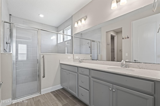 bathroom featuring vanity, a shower with shower door, and a textured ceiling