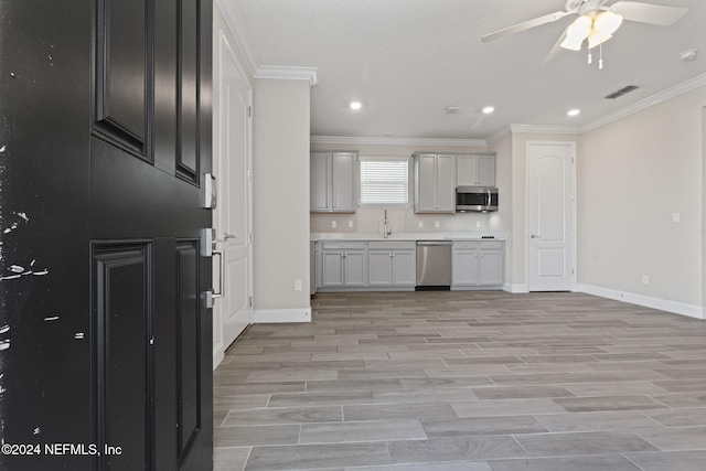 kitchen with ceiling fan, crown molding, light wood-type flooring, and stainless steel appliances