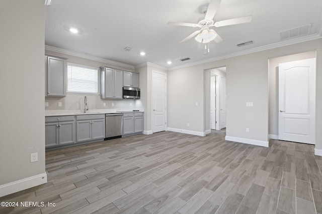 kitchen featuring gray cabinetry, sink, light wood-type flooring, ornamental molding, and stainless steel appliances