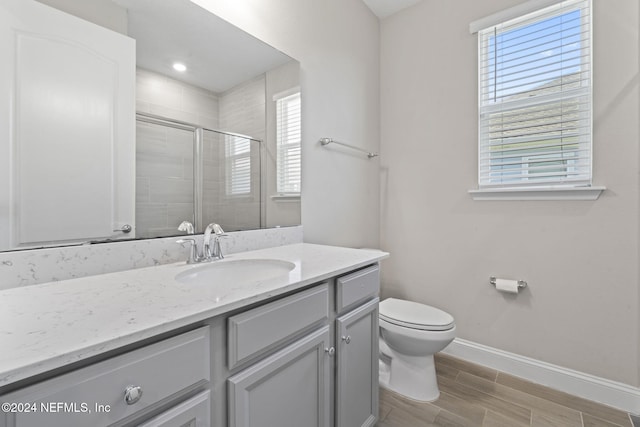 bathroom with vanity, a shower with shower door, and toilet