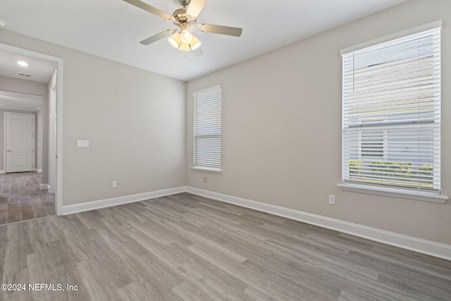 unfurnished room featuring hardwood / wood-style floors, ceiling fan, and a wealth of natural light