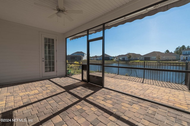 unfurnished sunroom with ceiling fan and a water view