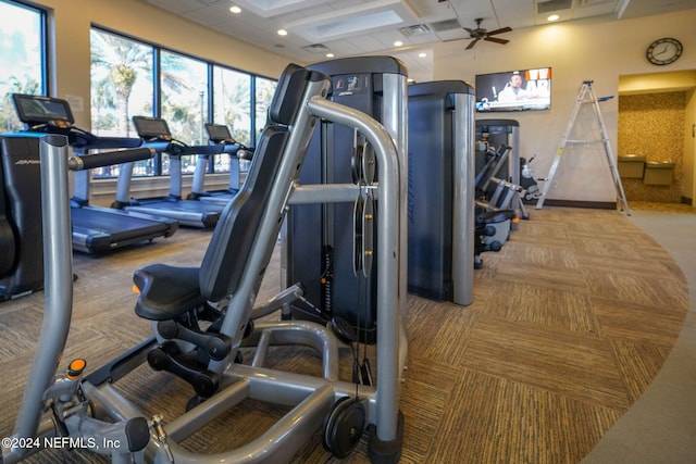 exercise room with ceiling fan, light colored carpet, and coffered ceiling