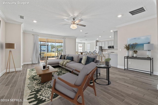 living room featuring hardwood / wood-style floors, a textured ceiling, and crown molding