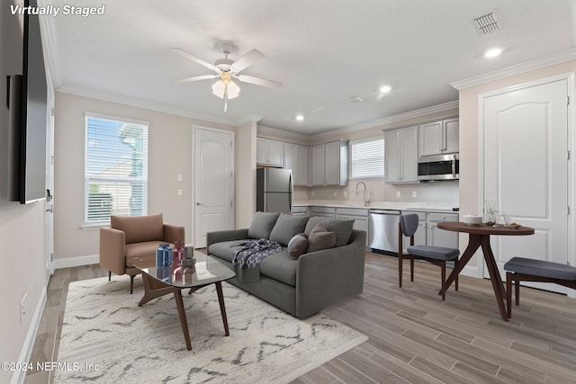 living room with ceiling fan, light hardwood / wood-style floors, sink, and crown molding