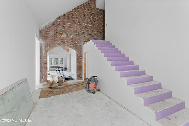 stairway featuring brick wall and concrete floors