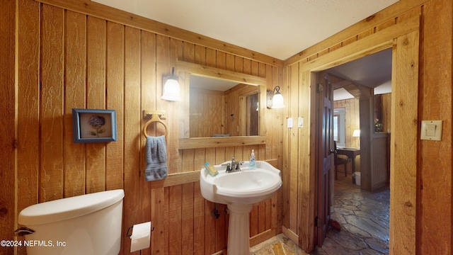 bathroom featuring toilet and wood walls