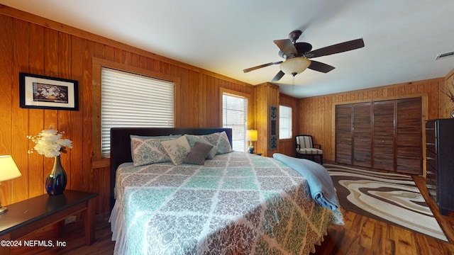 bedroom featuring dark hardwood / wood-style flooring, ceiling fan, a closet, and wood walls