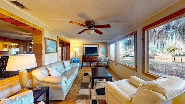 living room with ceiling fan and wood walls