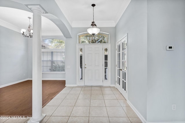 foyer entrance featuring an inviting chandelier, light hardwood / wood-style flooring, crown molding, and ornate columns