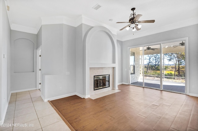 unfurnished living room featuring light wood-type flooring, ornamental molding, and a tile fireplace