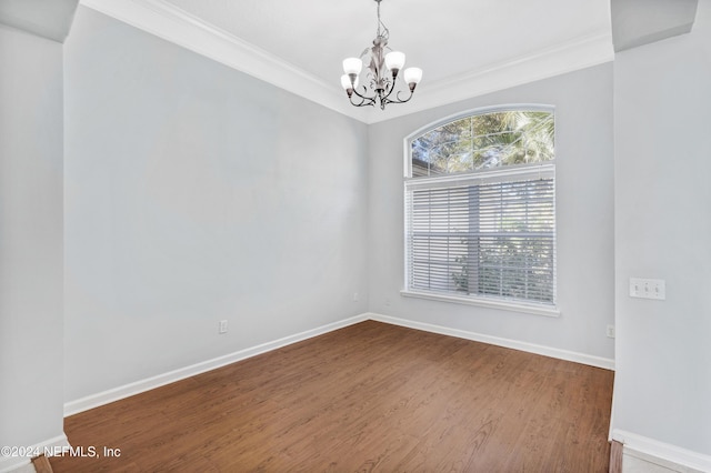 spare room with hardwood / wood-style flooring, ornamental molding, and an inviting chandelier