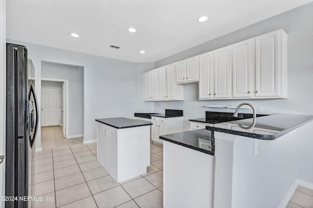 kitchen featuring kitchen peninsula, black refrigerator, and white cabinets