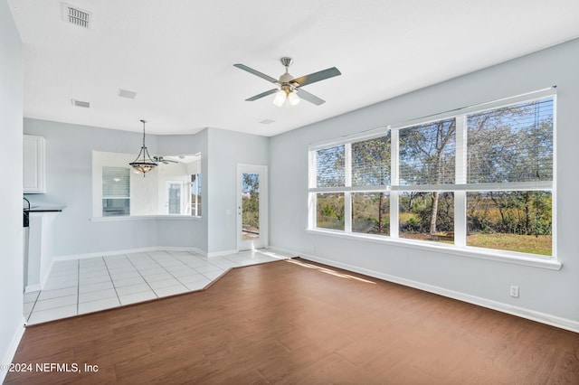 unfurnished room featuring ceiling fan with notable chandelier and light wood-type flooring