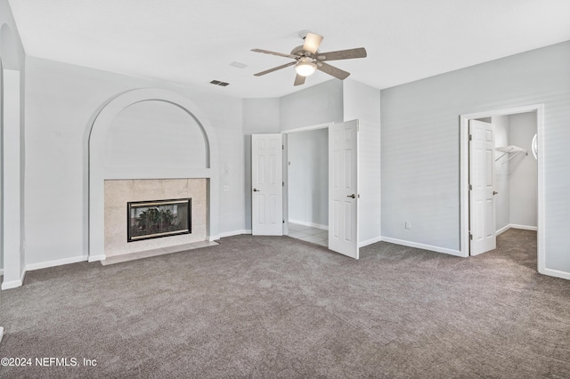 unfurnished living room with a tiled fireplace, ceiling fan, and carpet