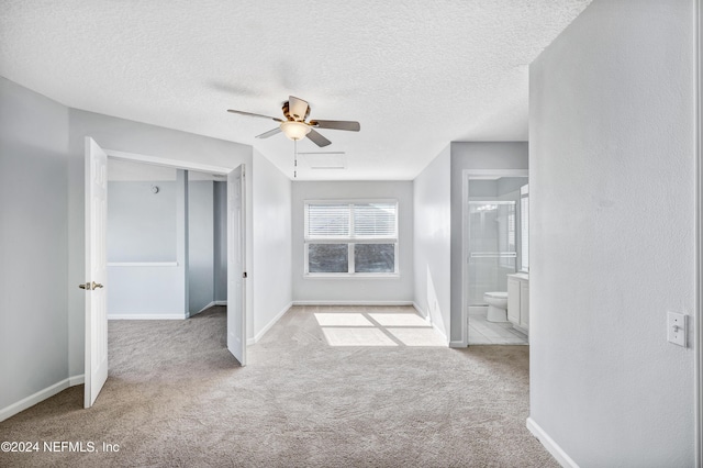 interior space featuring light carpet, a textured ceiling, connected bathroom, and ceiling fan