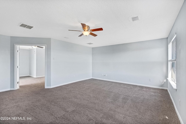 empty room featuring a textured ceiling and dark carpet