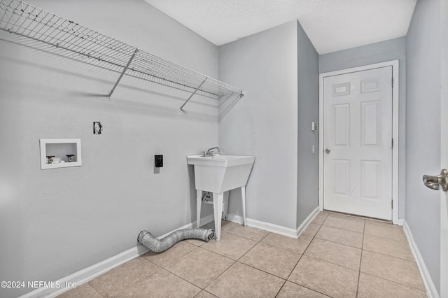 laundry area with hookup for a washing machine, light tile patterned floors, and a textured ceiling