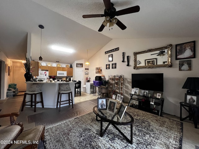 living room featuring a textured ceiling, ceiling fan, vaulted ceiling, and light wood-type flooring