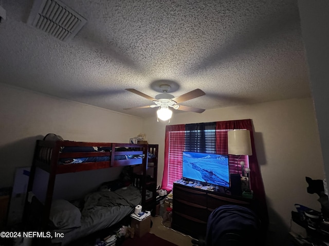 bedroom with ceiling fan and a textured ceiling