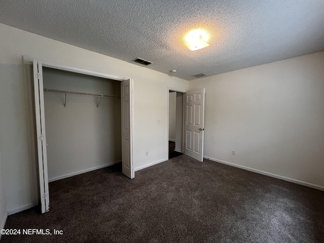 unfurnished bedroom with dark colored carpet, a textured ceiling, and a closet