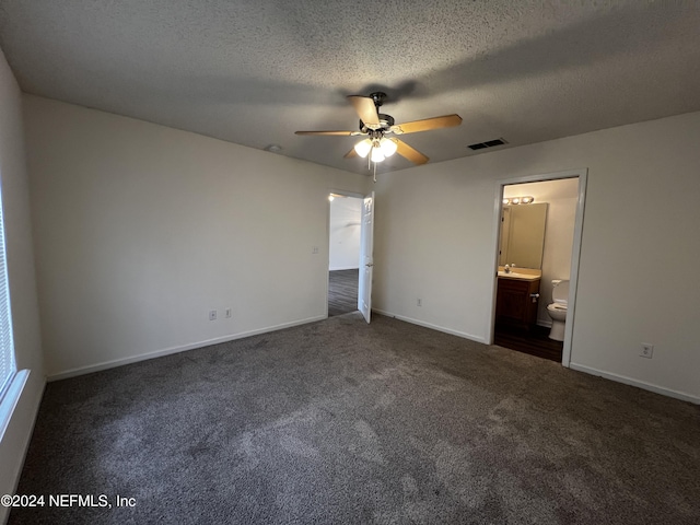 unfurnished bedroom featuring ceiling fan, dark carpet, a textured ceiling, and connected bathroom