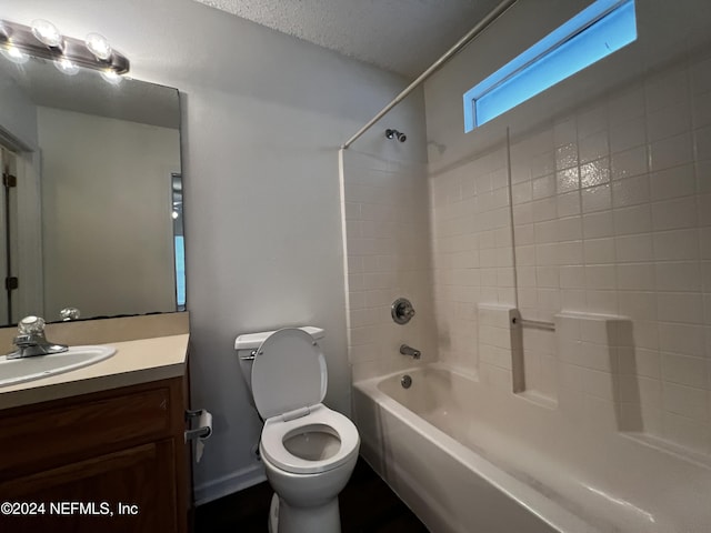 full bathroom featuring tiled shower / bath combo, toilet, a textured ceiling, and vanity