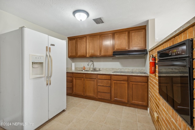 kitchen featuring light stone countertops, a textured ceiling, sink, and black appliances