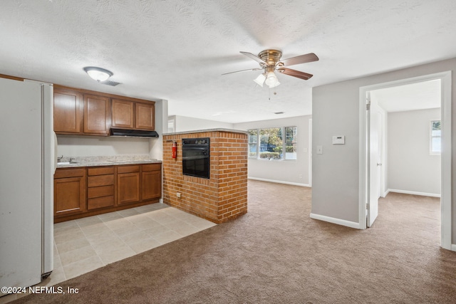 kitchen featuring a textured ceiling, light colored carpet, double oven, ceiling fan, and white fridge