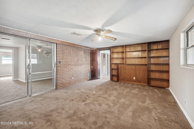 unfurnished bedroom featuring ceiling fan, carpet floors, a textured ceiling, and brick wall