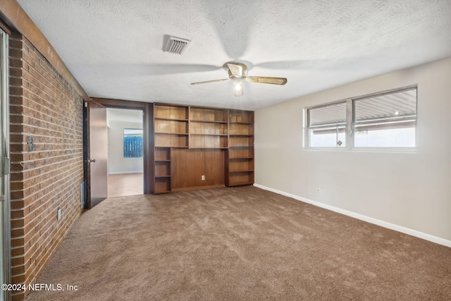 unfurnished bedroom featuring carpet, a textured ceiling, and brick wall