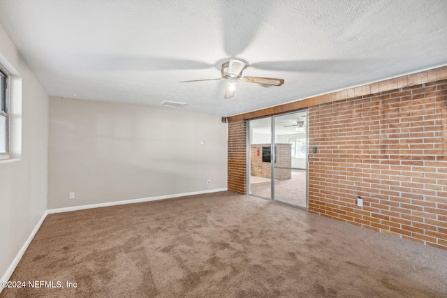 unfurnished room featuring ceiling fan, carpet floors, a textured ceiling, and brick wall