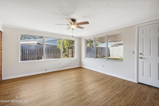 spare room with ceiling fan, ornamental molding, a textured ceiling, and light hardwood / wood-style flooring