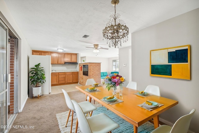 dining area featuring ceiling fan with notable chandelier, light colored carpet, and a textured ceiling