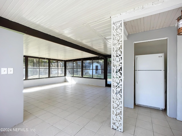 unfurnished living room with beamed ceiling, wood ceiling, and light tile patterned floors