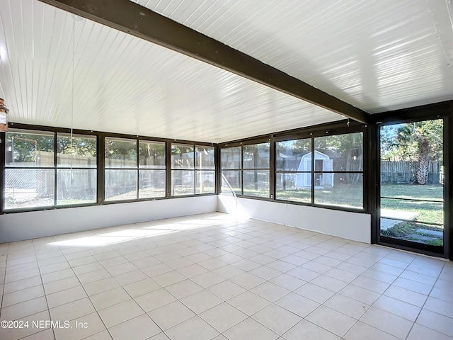 unfurnished sunroom featuring beamed ceiling and a wealth of natural light