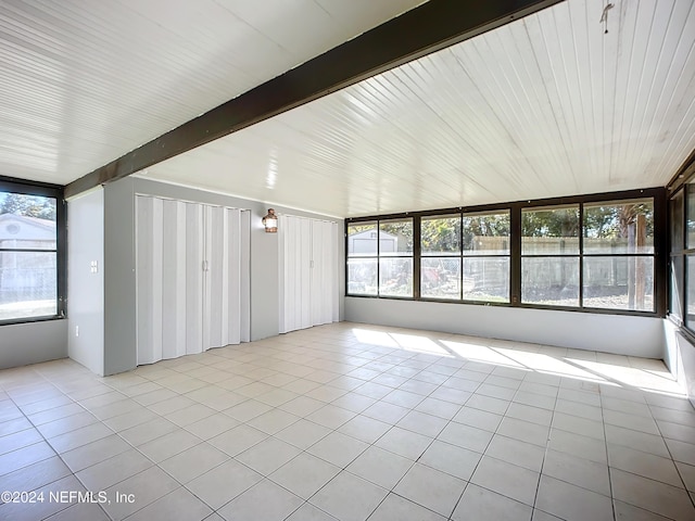 unfurnished sunroom featuring beamed ceiling