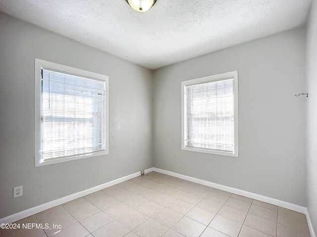 tiled spare room featuring a wealth of natural light and a textured ceiling