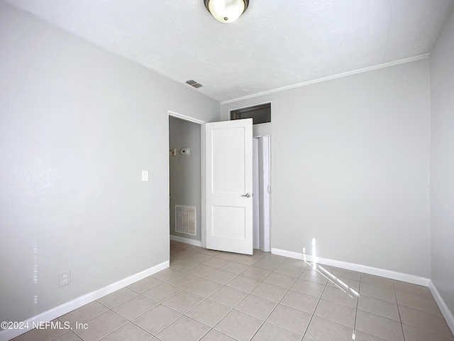 unfurnished room with light tile patterned floors and ornamental molding