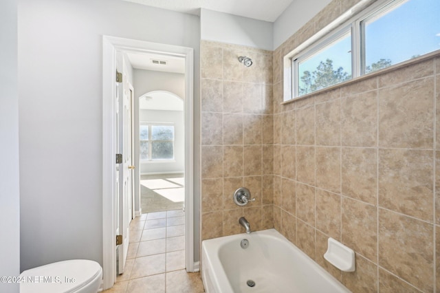 bathroom featuring tile patterned flooring, tiled shower / bath combo, and toilet