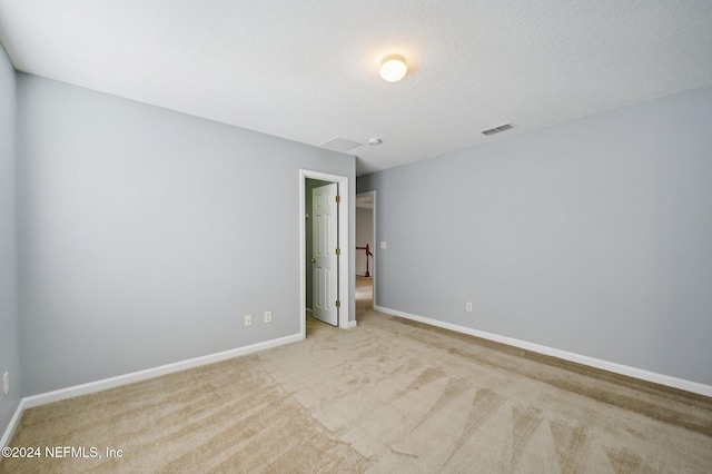 unfurnished bedroom with a textured ceiling and light colored carpet