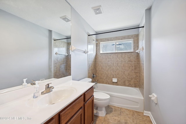 full bathroom featuring tile patterned floors, vanity, tiled shower / bath combo, a textured ceiling, and toilet