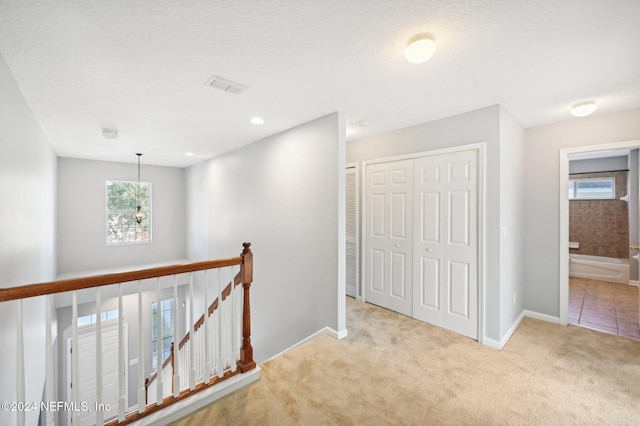 hall featuring light colored carpet and a textured ceiling