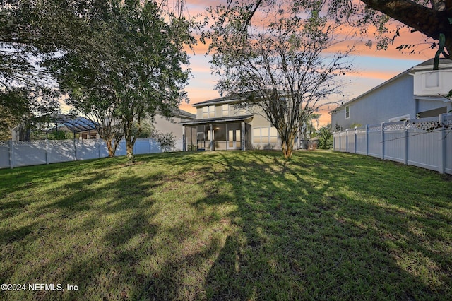 yard at dusk featuring a sunroom