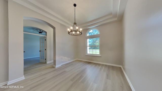 unfurnished room with a tray ceiling and light wood-type flooring