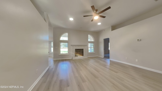 unfurnished living room with a tiled fireplace, light hardwood / wood-style floors, and ceiling fan