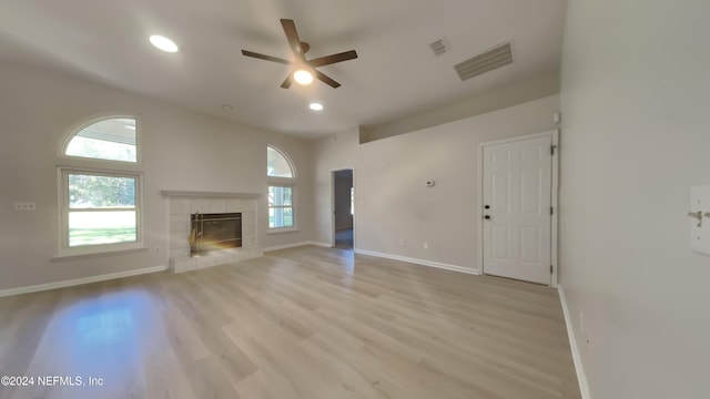 unfurnished living room with a tiled fireplace, light hardwood / wood-style floors, and ceiling fan