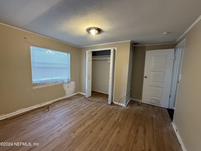 unfurnished bedroom featuring a textured ceiling, light hardwood / wood-style flooring, a closet, and ornamental molding